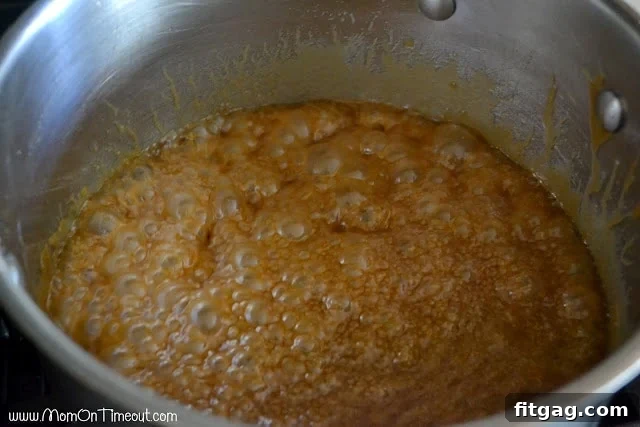 Creamy, golden homemade caramel sauce simmering in a pot, achieving its perfect consistency.