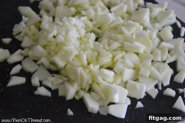 A close-up of finely diced apples on a cutting board, ready to be incorporated into the sticky buns.