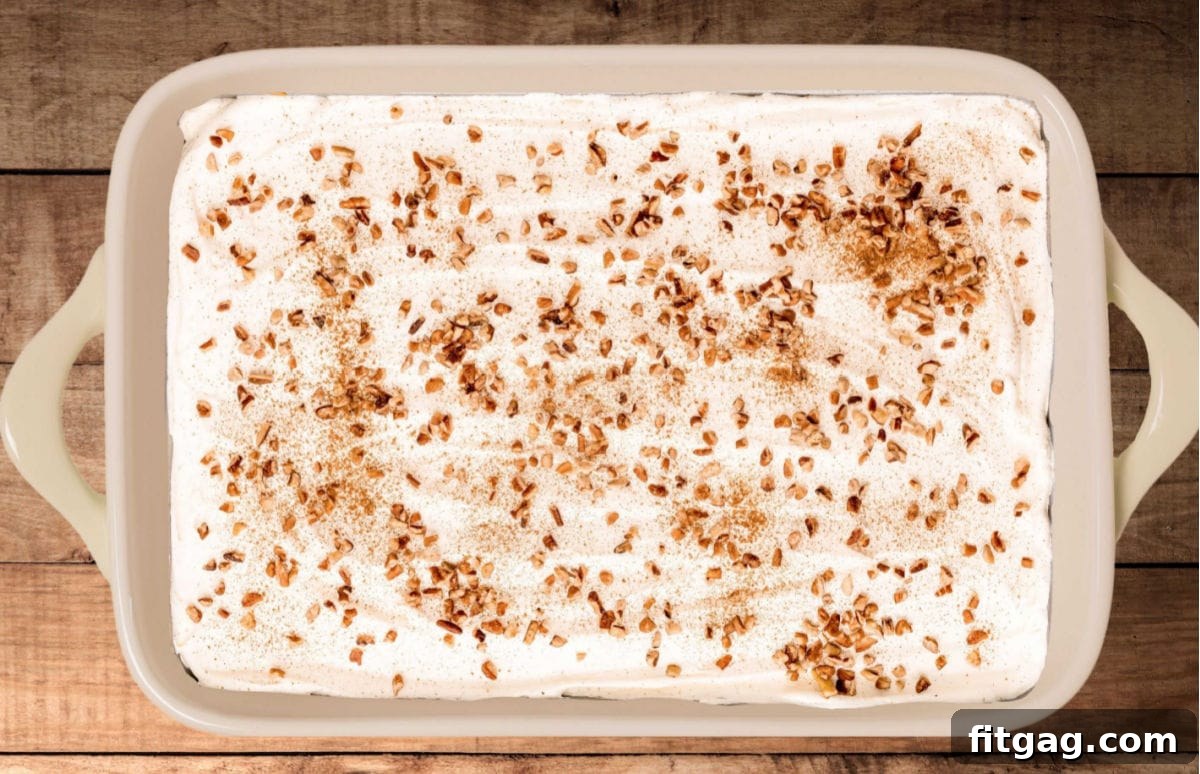 Harvest Pumpkin Bliss 4 A full 9x13 inch baking dish of Pumpkin Delight, with its top layer of whipped cream, toasted pecans, and a light dusting of pumpkin pie spice clearly visible, ready for chilling.
