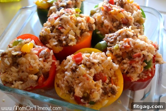 Stuffed bell peppers arranged in a greased baking dish, topped with cheese and covered with foil, ready for the oven.