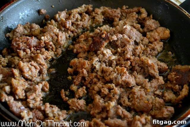 Browned Italian sausage and ground beef cooking in a skillet, seasoned with salt and pepper.
