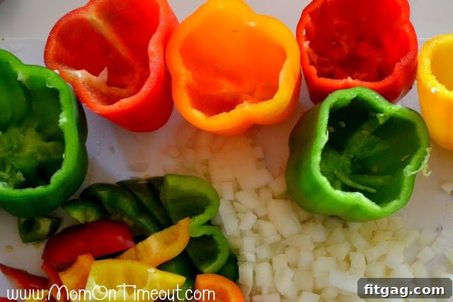 Fresh bell peppers with tops removed, seeds and veins scooped out, alongside a diced onion and bell pepper tops.