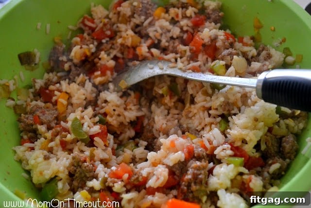 A spoon mixing all the ingredients for the stuffed pepper filling in a large bowl, ensuring even distribution.