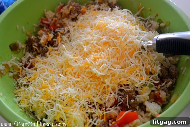 Shredded Mexican blend cheese added to the stuffed pepper filling mixture in a large bowl, ready to be stirred.