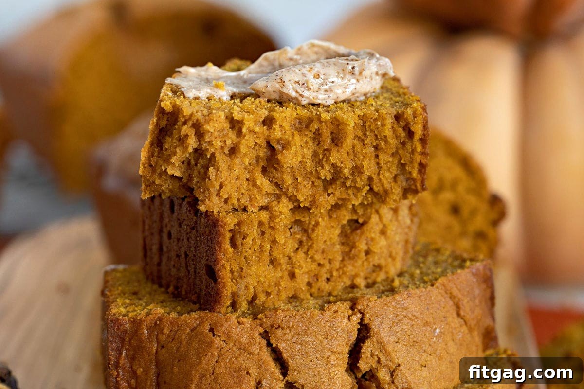 A close-up of a slice of pumpkin bread generously topped with a dollop of cinnamon brown sugar butter.