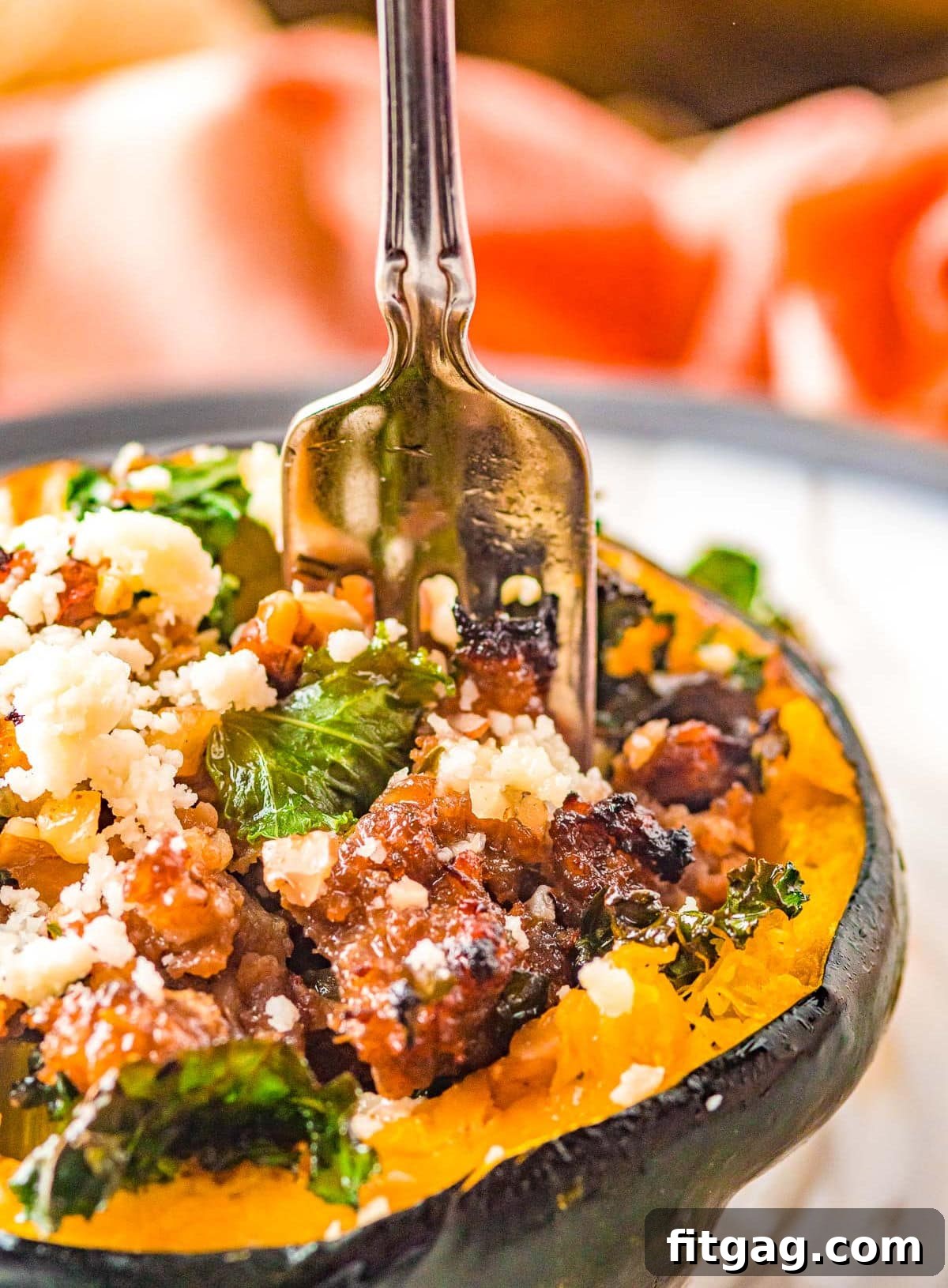 fork going into acorn squash that has been filled with a sausage stuffing mixture.