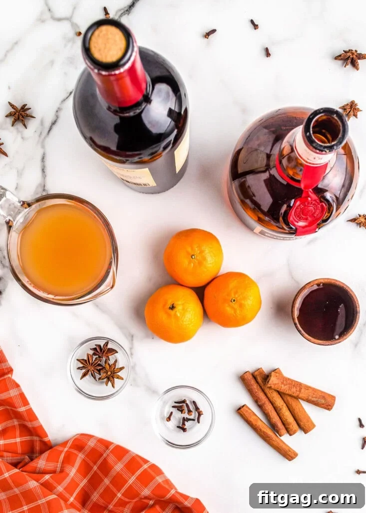 A beautiful flat lay of all the essential ingredients laid out neatly and ready for use in the mulled wine recipe. The arrangement includes whole spices, fresh fruit, bottles of wine and spirits, and sweeteners, all indicating a delicious preparation.
