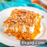 pumpkin cake sitting on white plate with bright blue napkin in the background. topped with cool whip and heath toffee bits.