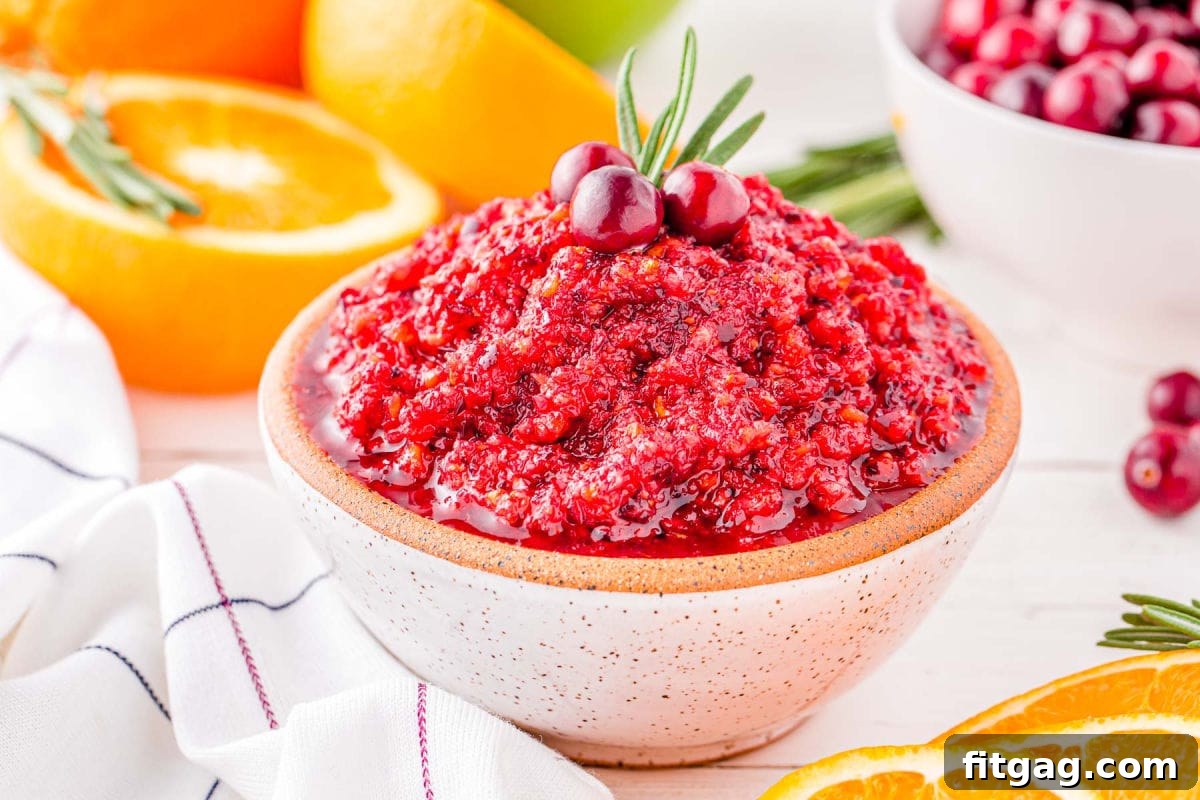 A beautifully presented small white clay bowl filled with glossy cranberry orange relish, ready to be served, highlighting its vibrant color and fresh texture.