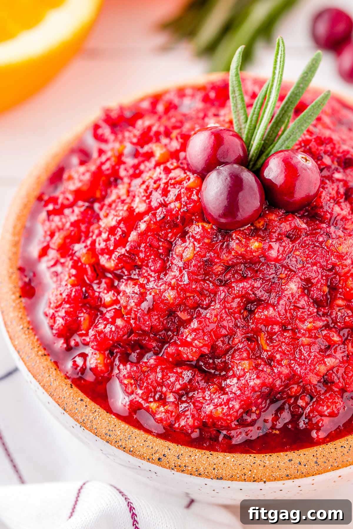 A close-up view of the finely chopped, vibrant cranberry orange relish in a small white bowl, ready for serving, showcasing its fresh texture.