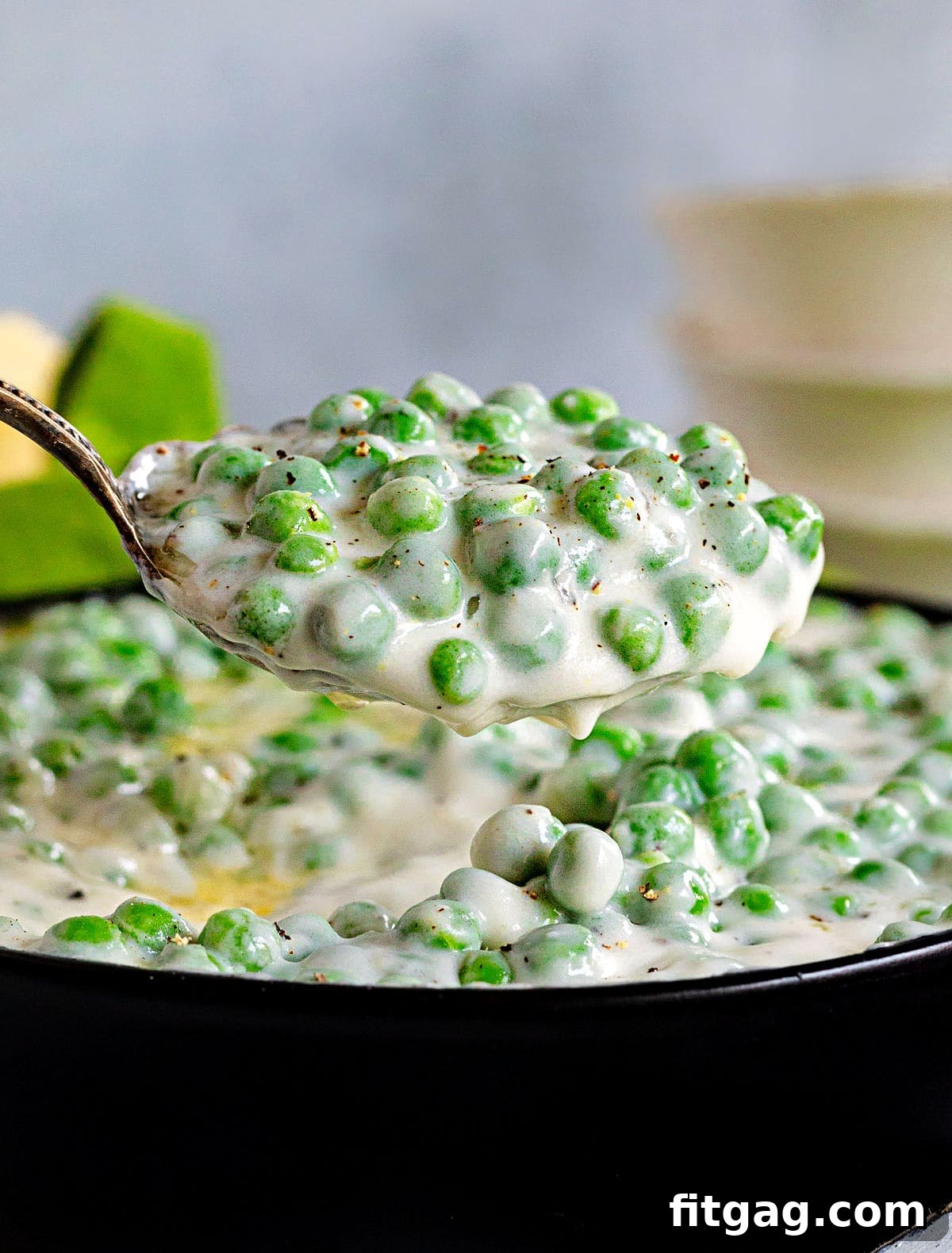 Velvet Peas 2 A large spoonful of perfectly cooked creamed peas, ready to be served from a black bowl.