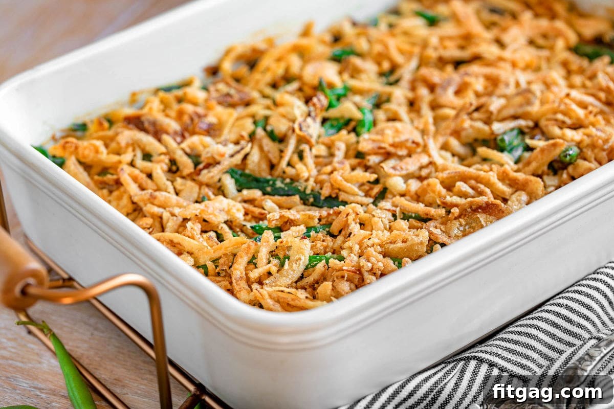Crispy Onion Green Bean Delight 5 A side view of the finished green bean casserole recipe, glistening with homemade sauce and topped with golden fried onions, served in a large white casserole dish.