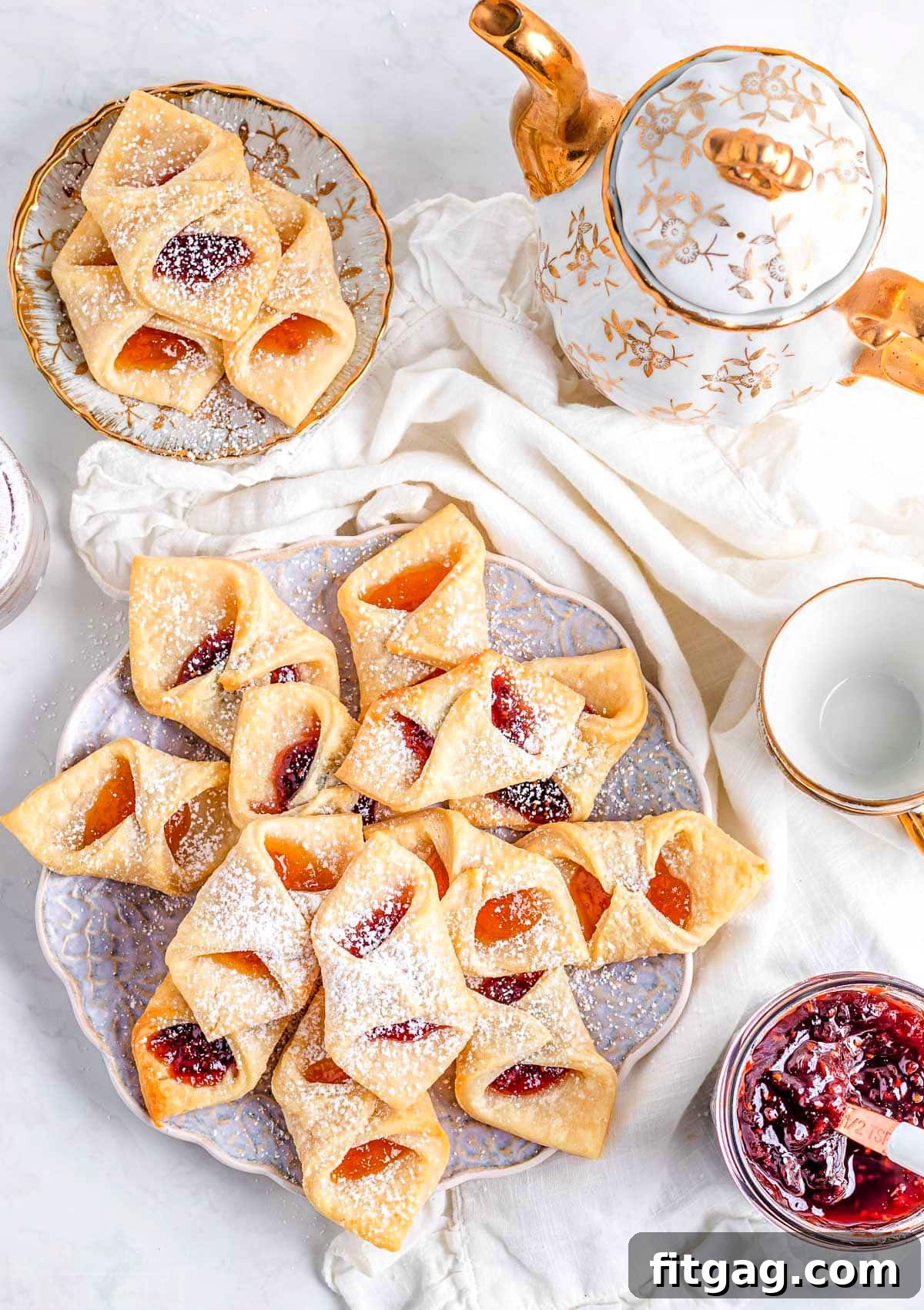 A plate of Kolacky cookies with a small jar of jam, viewed from above in a flat lay style.
