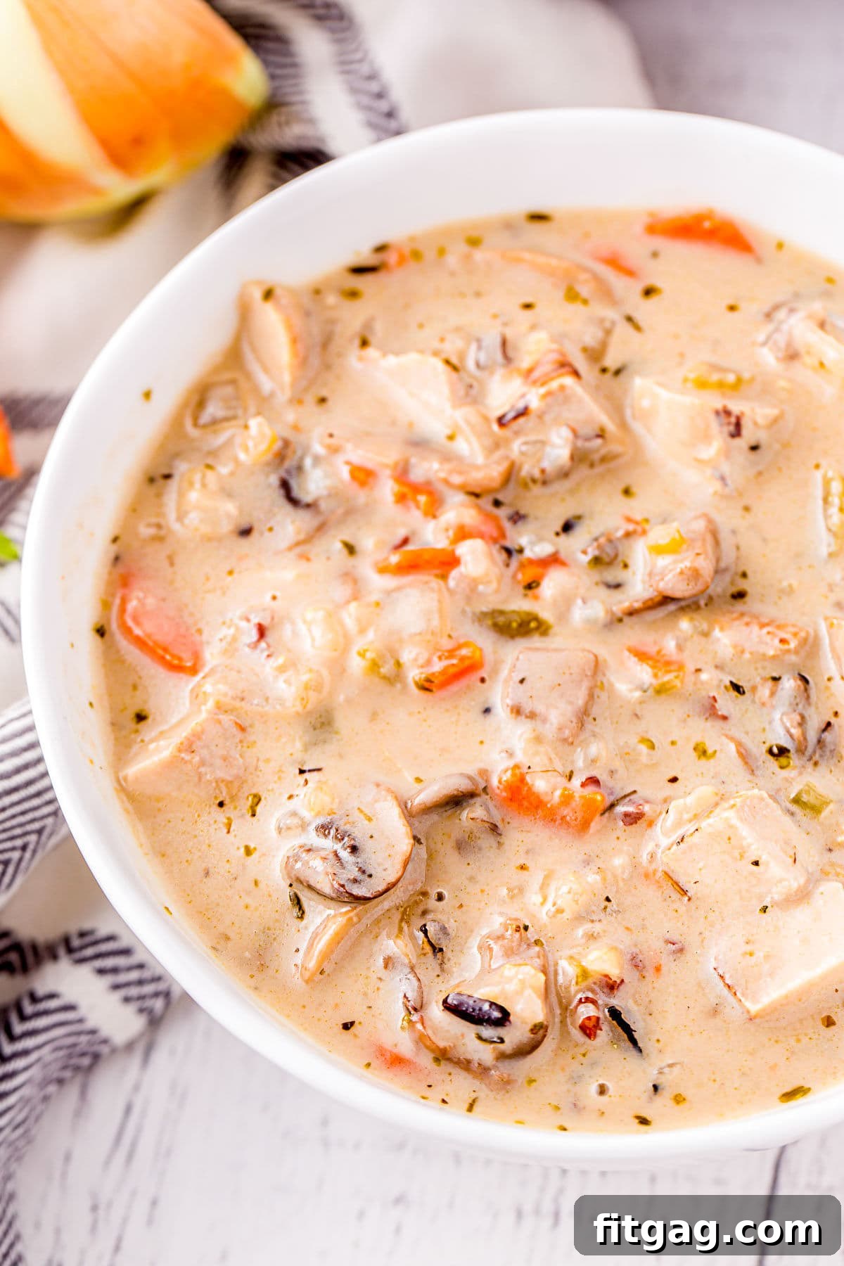 Close-up of creamy turkey and wild rice soup with mushrooms in a white bowl, ready to be enjoyed.