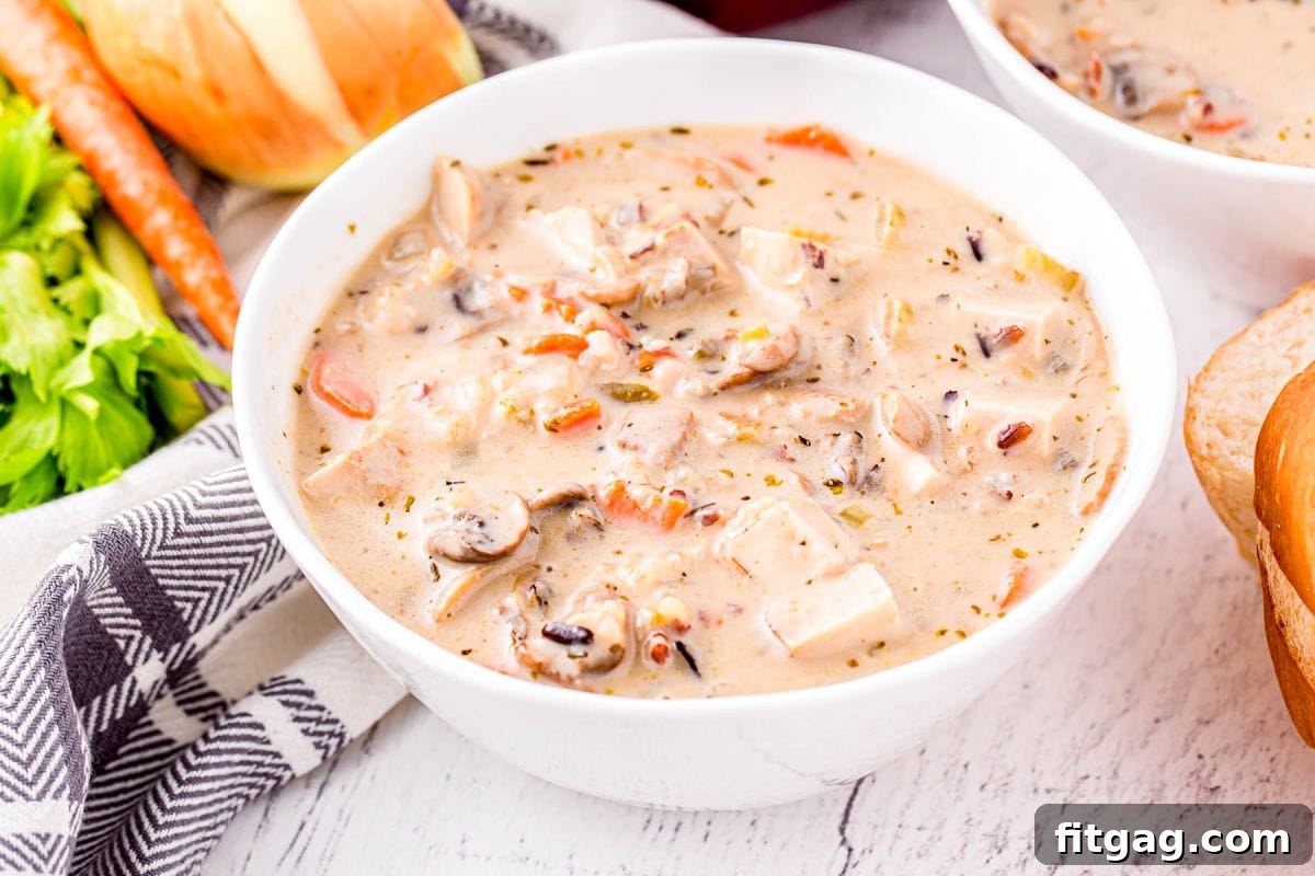 A white bowl filled with creamy turkey and wild rice soup, garnished with fresh herbs, ready to be served.
