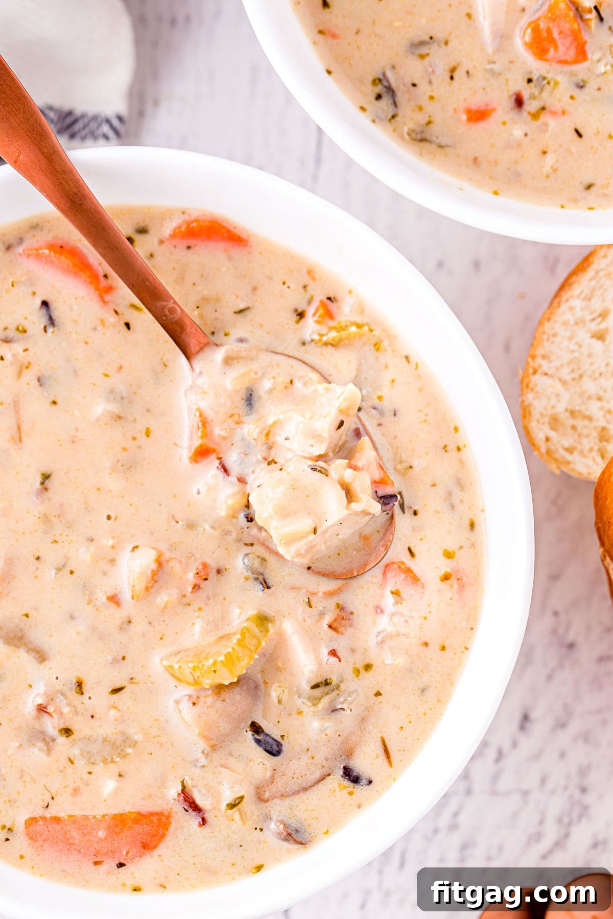 A close-up of a spoonful of creamy turkey and wild rice soup, showing the rich texture and delicious ingredients, served in a white bowl.