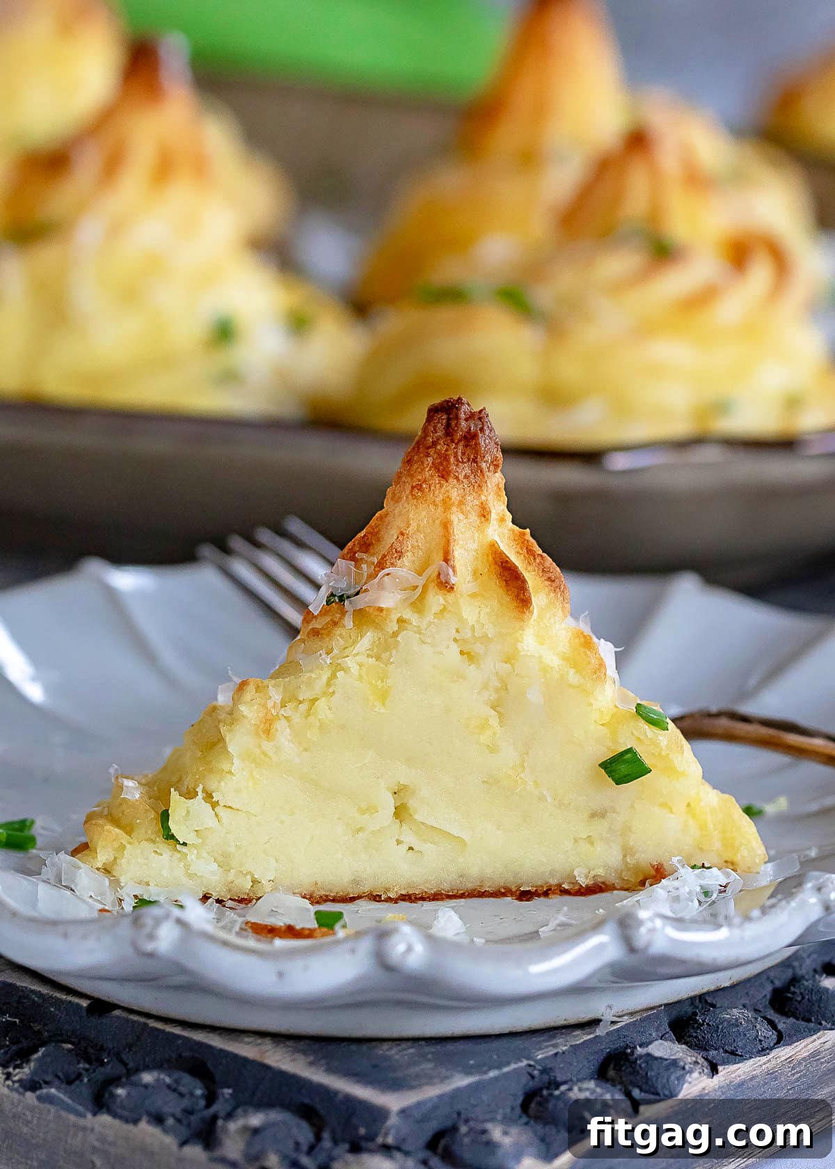 One Duchess potato serving, perfectly cut in half, rests on a small white plate, revealing its irresistibly creamy and smooth interior.