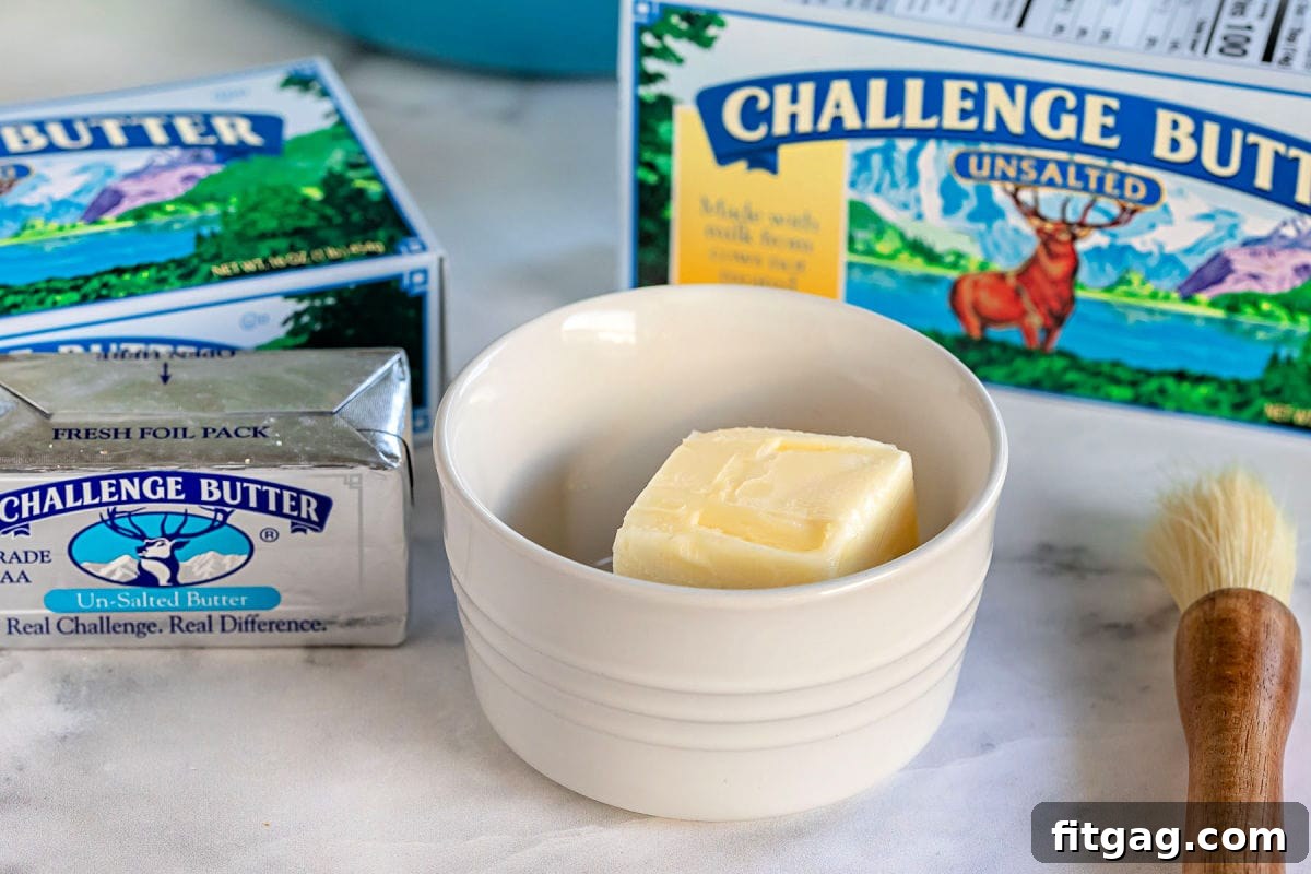 A small white bowl filled with creamy, golden butter, ready to be melted and incorporated into the recipe.