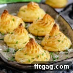 Large brown tray with six duchess potatoes garnished with Parmesan cheese and snipped chives.
