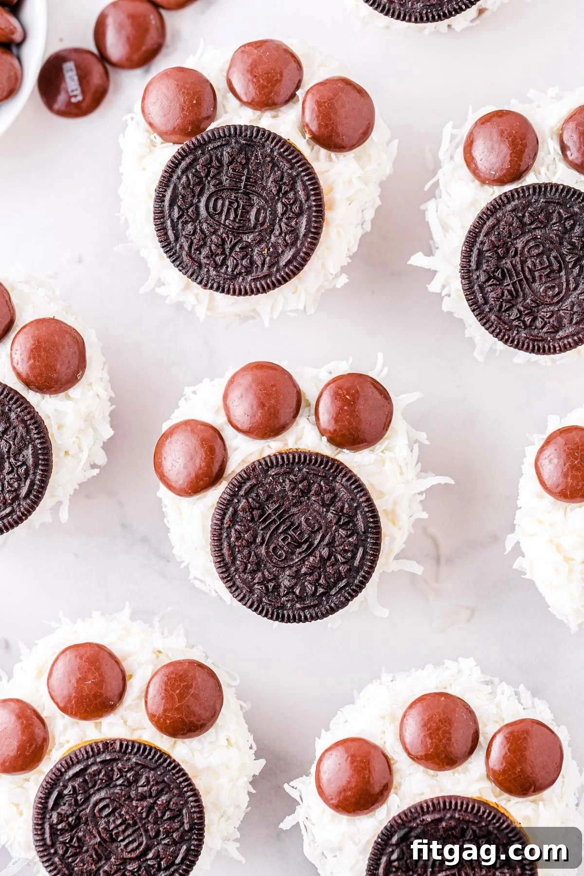 six cupcakes decorated to look like polar bear paws with oreos and coconut.