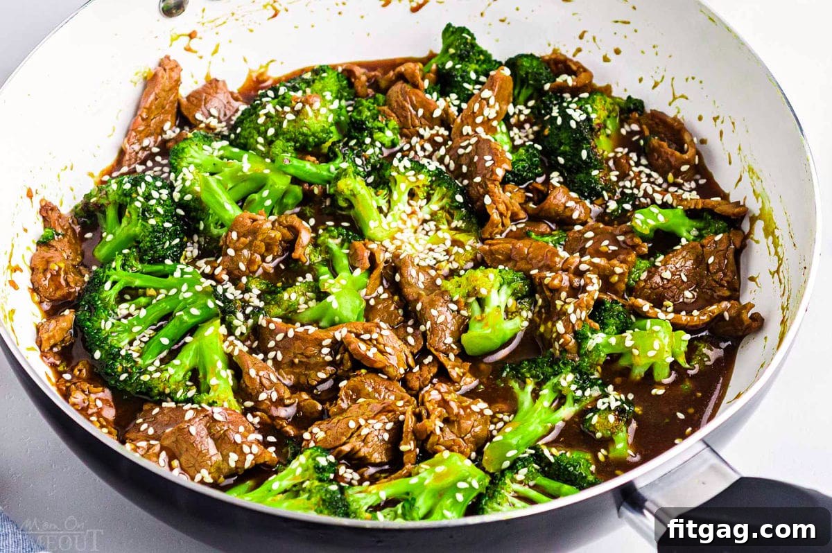 Restaurant-Style Beef and Broccoli Stir-fry 3 A close-up view of the delicious Beef and Broccoli stir fry, still in the white skillet, adorned with white sesame seeds. The steam rising gently suggests its freshness and readiness to be served.