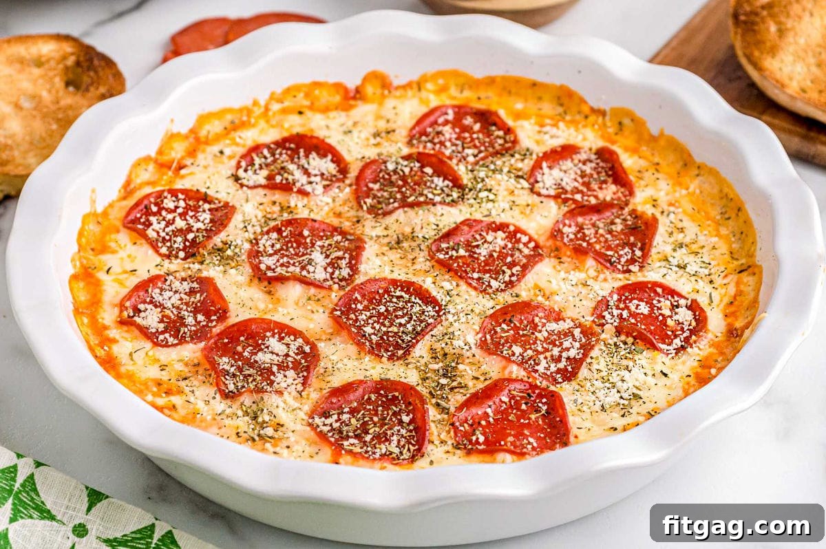 Baked Cheesy Pizza Dip 4 A close-up view of the golden-brown baked pepperoni pizza dip, generously topped with fresh Italian seasoning and grated Parmesan cheese, showcasing its delicious texture.