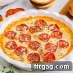 pizza dip baked in white pie dish topped with pepperoni and parmesan cheese. plate of toasted baguette and a bowl of chips are set off to the side.