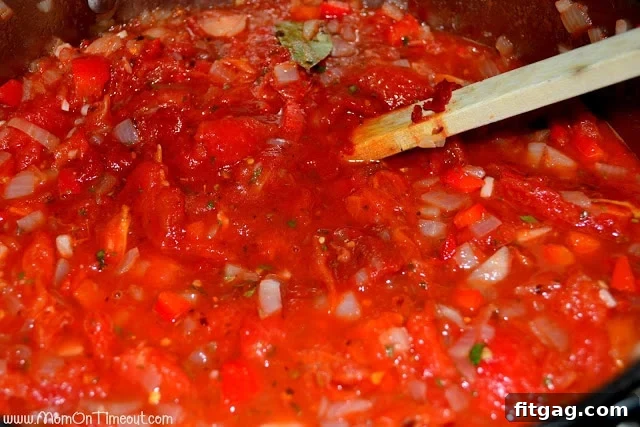 Homemade pasta sauce simmering in a large pot on the stove, achieving perfect thickness and rich flavor.