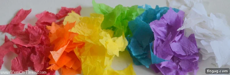 Sparkling Rainbow Suncatchers 3 Close-up of torn colored tissue paper pieces, ready for a stained glass rainbow craft, demonstrating fine motor skill development.
