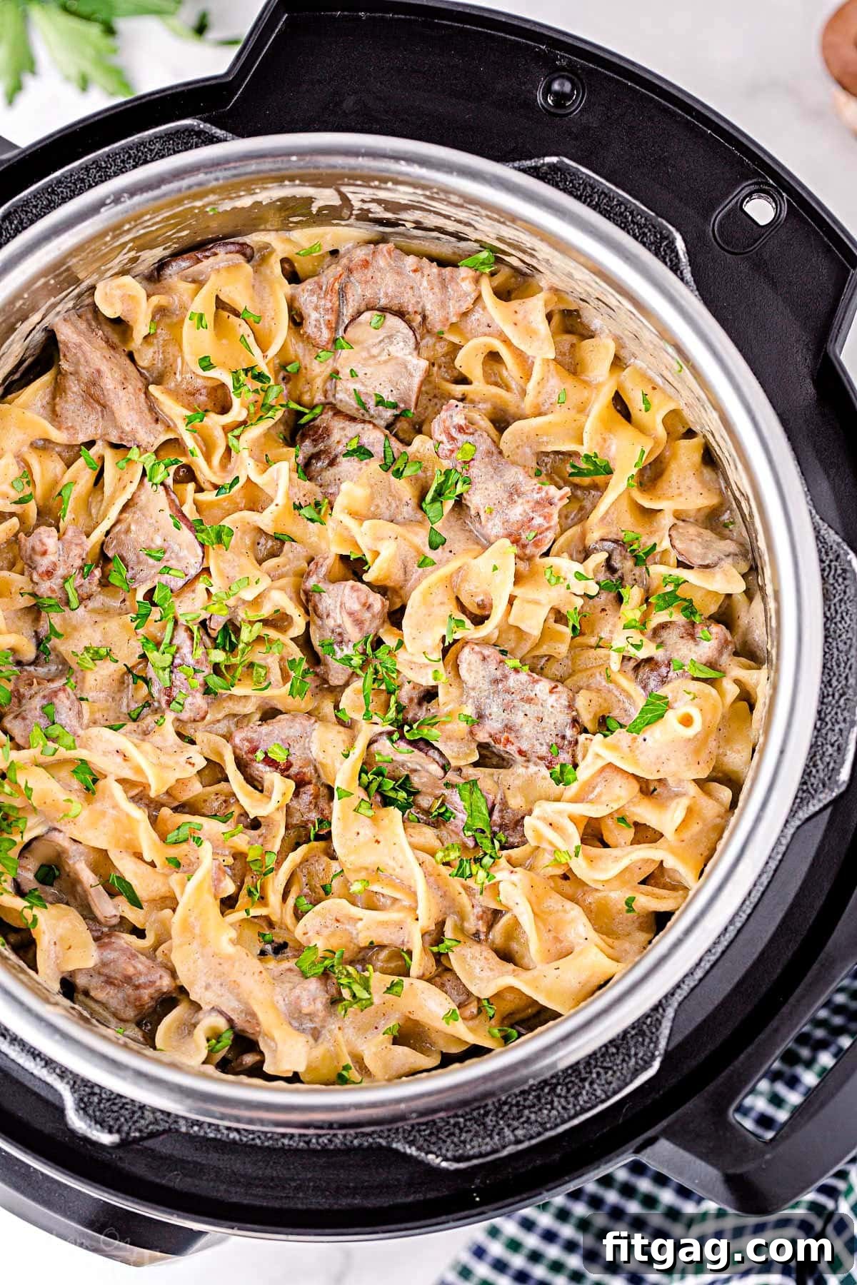 Top down view of Beef Stroganoff cooked directly in the Instant Pot, garnished with fresh parsley and ready to be served. The rich color of the sauce and the tender beef pieces are clearly visible.