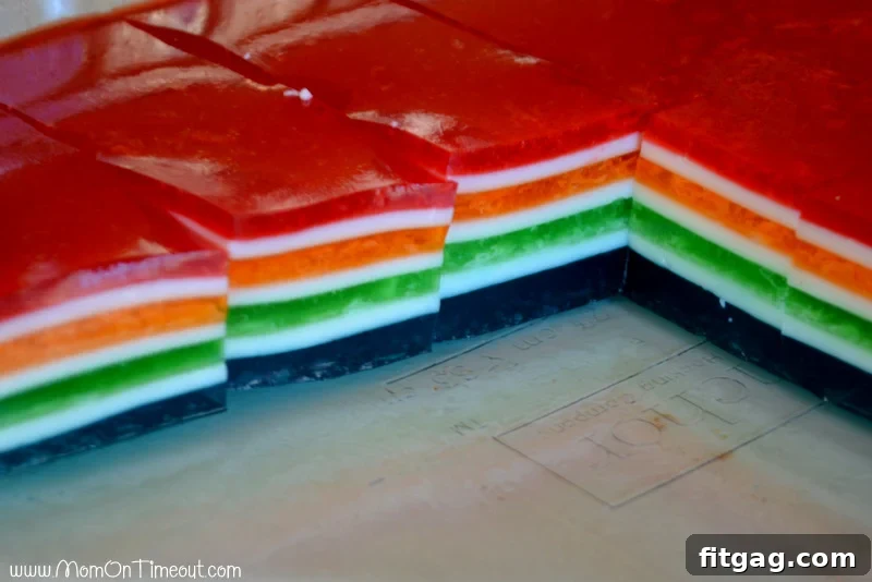 A dish showing several distinct layers of Rainbow Jello before being cut into cubes, highlighting the vibrant colors and smooth transitions.