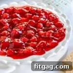 cheesecake dip topped with a can of cherry pie filling in a white scalloped pie plate.