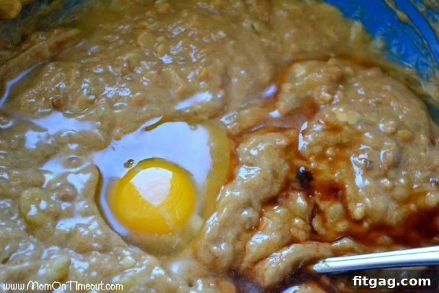 The wet batter for peanut butter banana bread, with a freshly cracked egg and vanilla extract waiting to be mixed in.