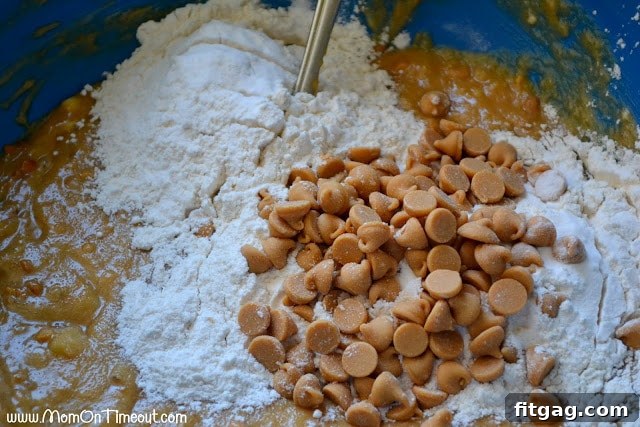 The peanut butter banana bread batter with all-purpose flour and Reese's Peanut Butter chips gently folded in, showcasing the mixing process.