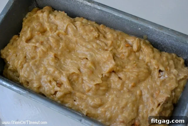 The greased and floured loaf pan now filled with the smooth and chunky peanut butter banana bread batter, ready for the oven.