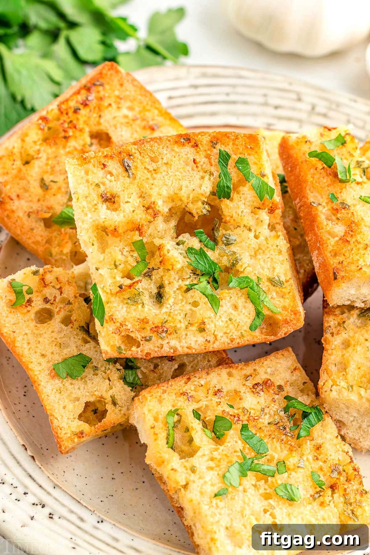 Crispy Air Fryer Garlic Bread 2 plate topped with 6 or 7 pieces of garlic bread that was made in the air fryer. garnished with fresh chopped parsley.