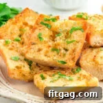 Crispy Air Fryer Garlic Bread 8 shot of garlic bread sliced and ready to serve off a white plate. fresh parsley garnish on the bread.