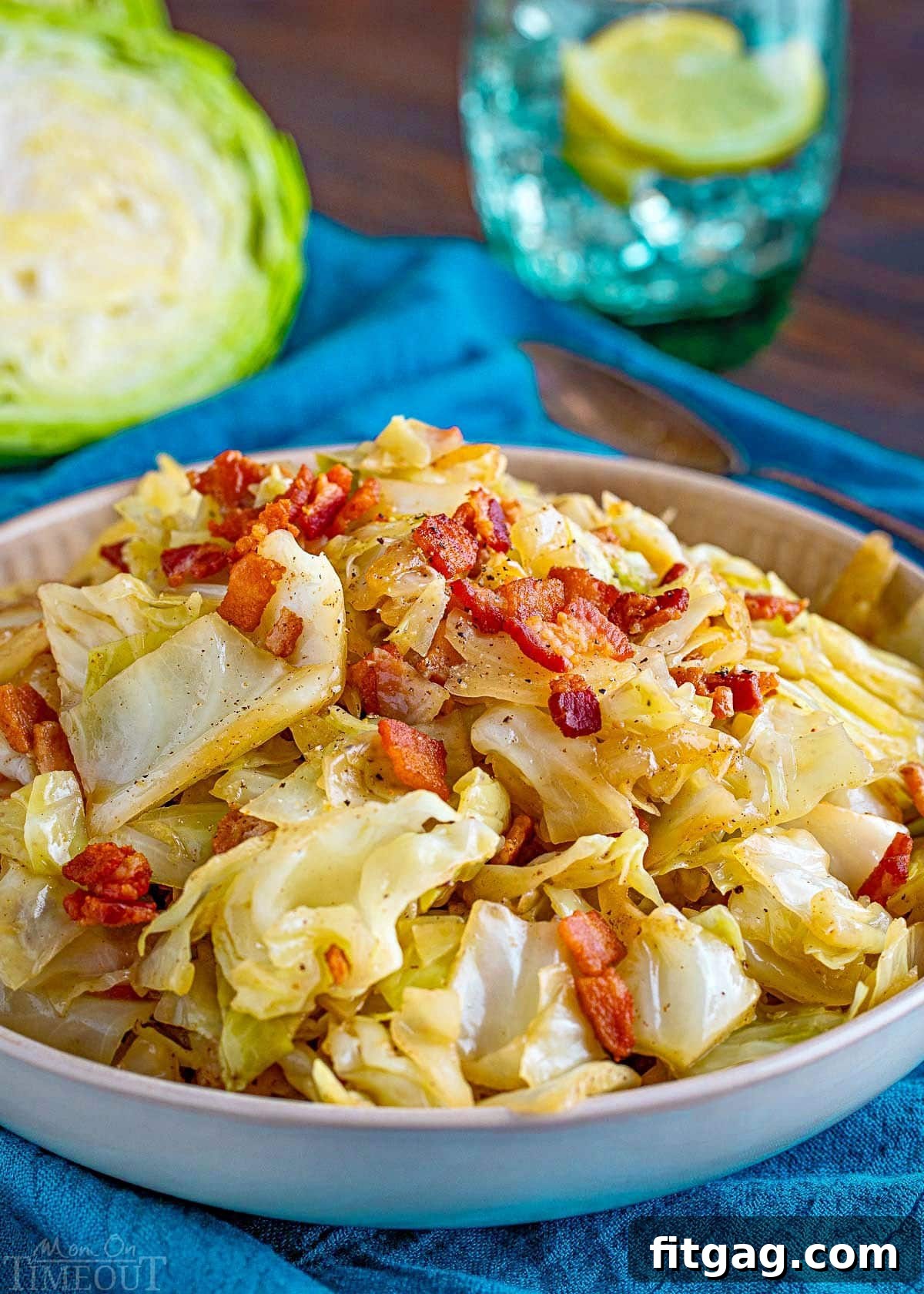 Golden Fried Cabbage 5 A shallow bowl, beautifully presented, filled with the hearty fried cabbage, complete with crispy bacon, sweet onions, and fragrant garlic. The bowl rests upon a bright teal napkin, and a fresh half-head of cabbage sits in the background, reinforcing the dish's fresh ingredients.