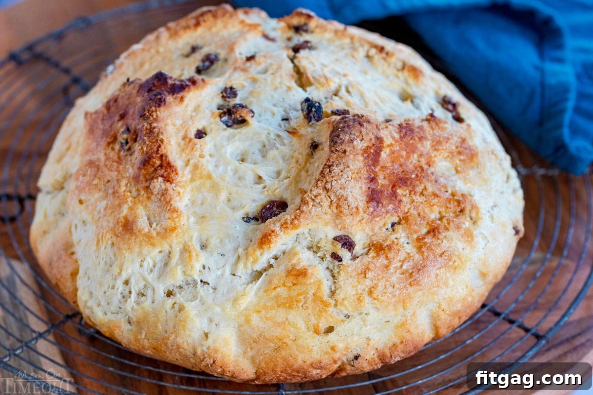 A freshly baked, golden-brown loaf of Irish Soda Bread cooling on a wire rack, showcasing its perfect round shape and rustic 'X' mark.
