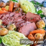 serving plate filled with slices of corned beef, cabbage wedges, carrots and creamer potatoes all ready to be enjoyed.