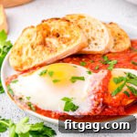 Eggs in purgatory plated with extra sauce and nicely toasted crusty bread. The dish is topped with chopped parsley.