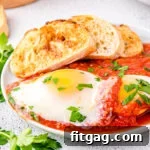 eggs in purgatory plated with extra sauce and nicely toasted crusty bread. The dish is topped with chopped parsley.