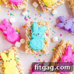 Gooey Peeps Cereal Bars 8 rice krispie treats decorated with white candy melts and sprinkles and topped with different colored Peeps. This is a top down view of the treats laid out on parchment paper.
