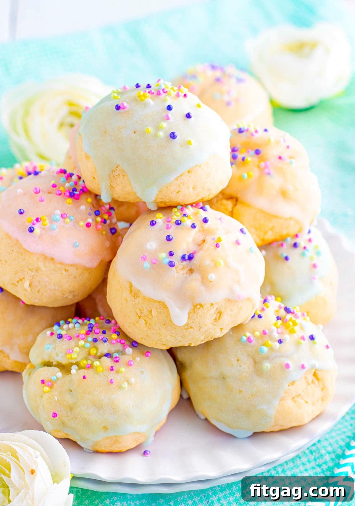 Sweet Italian Easter Cookie Delights 2 A beautiful display of colorful Italian Easter cookies piled high on a white scalloped plate, featuring various pastel glazes and festive sprinkles.