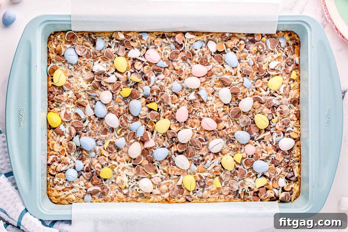 Whimsical Easter Magic Bars 5 light blue metal baking tray with baked magic cookie bars topped with cadbury eggs.