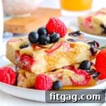 Oven Pancakes 9 Two square sheet pan pancakes stacked on a white plate with berries and syrup.