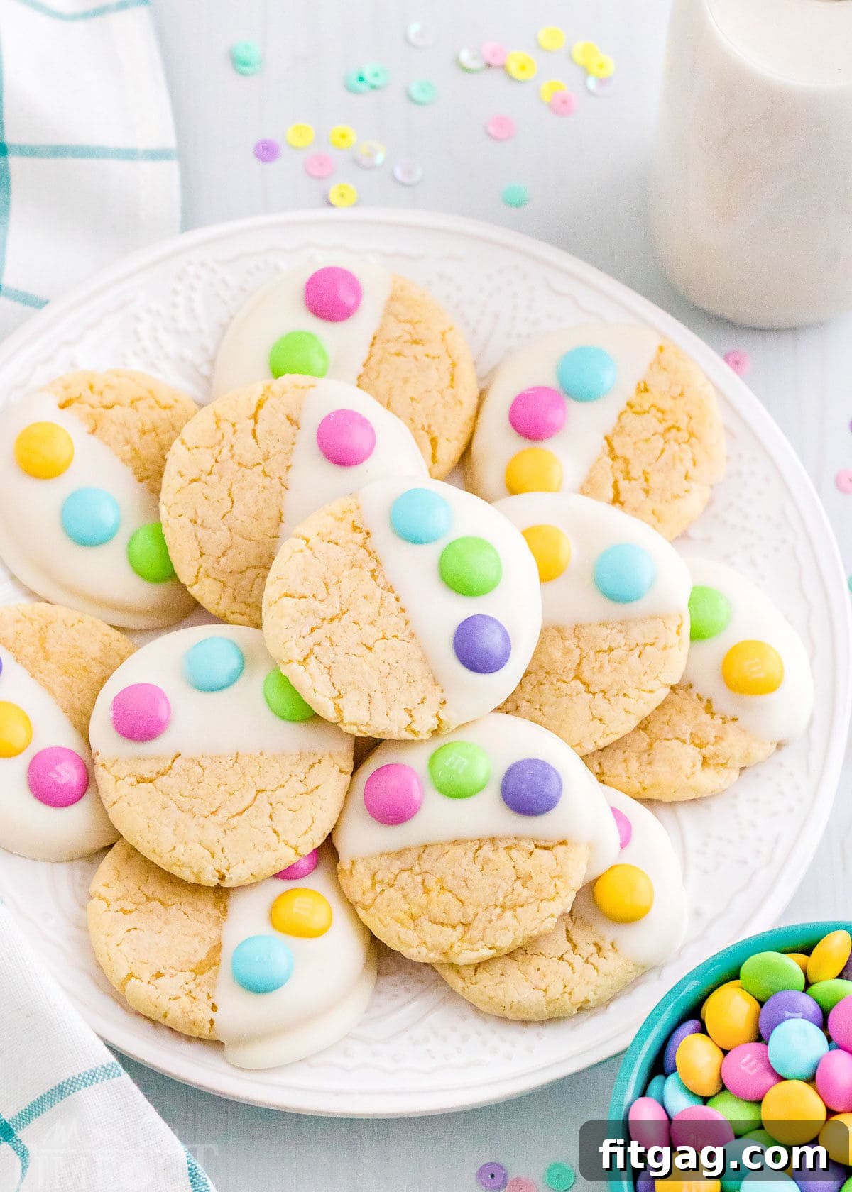 white plate filled with cake mix cookies dipped in candy melts and topped with three m&ms to resemble a bunny paw print.
