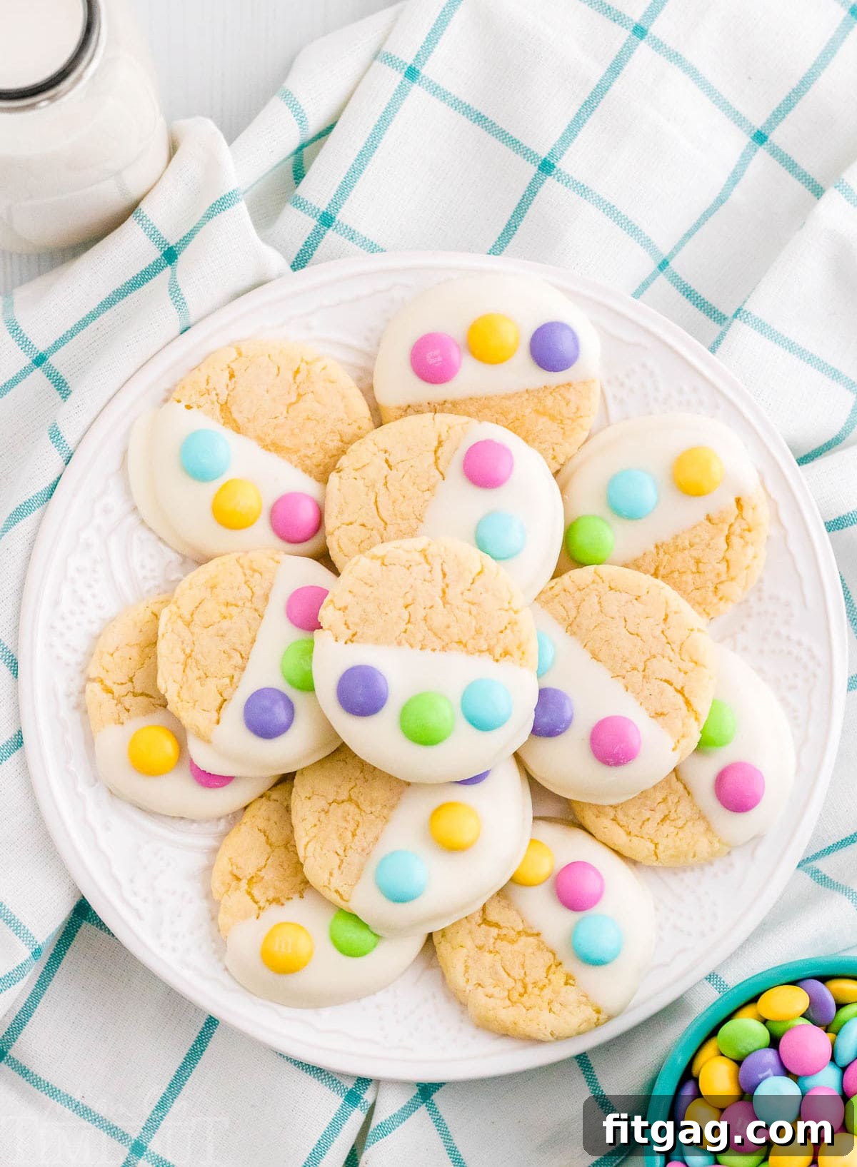 white plate filled with cake mix cookies dipped in candy melts and topped with three m&ms to resemble a bunny paw print.