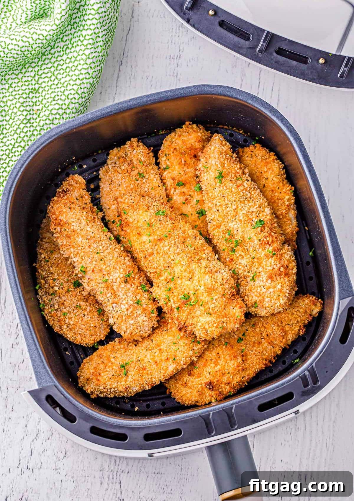 Top-down view of perfectly cooked golden-brown air fryer chicken tenders arranged in an air fryer basket.
