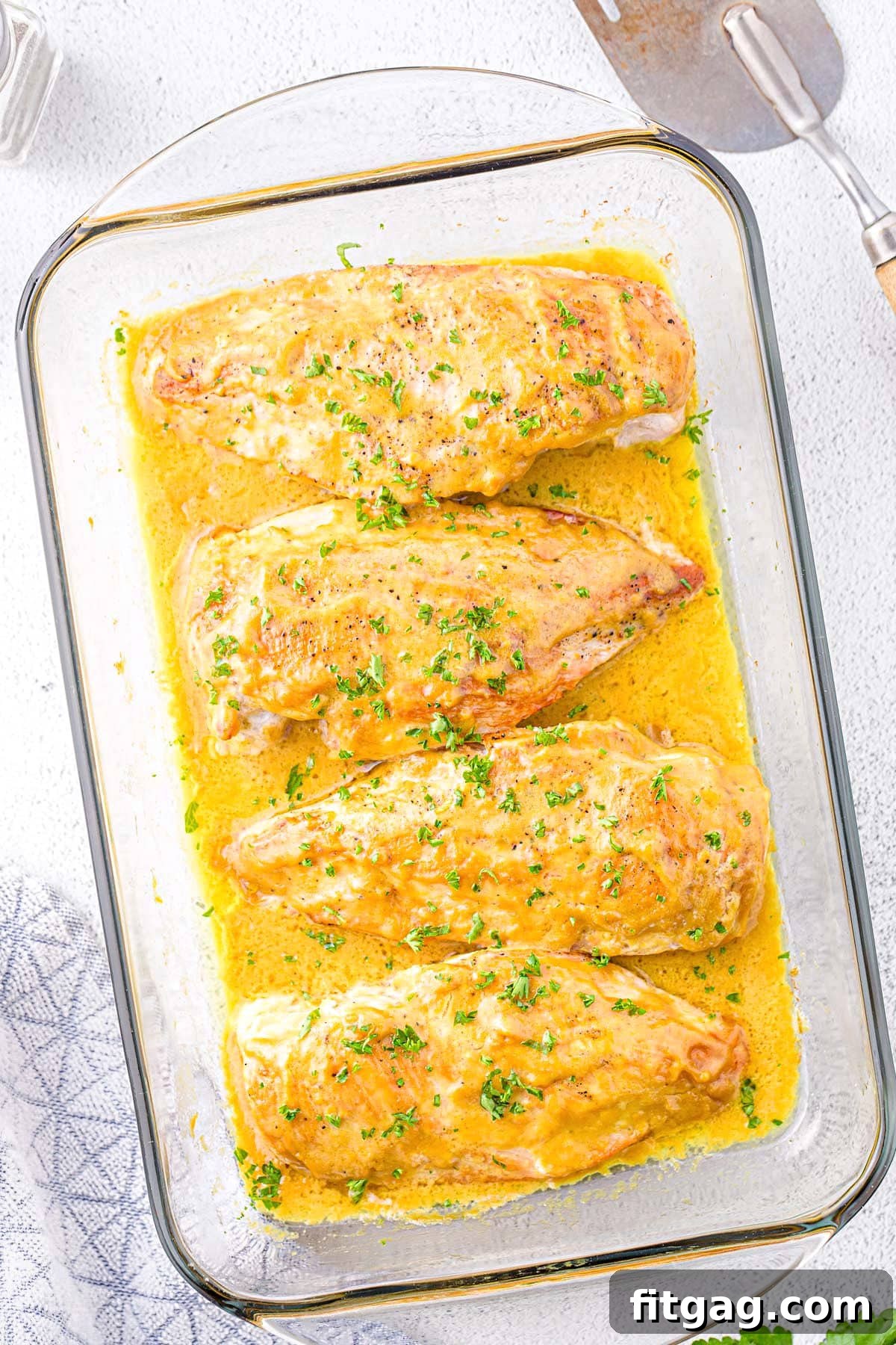 Crispy Honey Mustard Chicken Bites 6 A top-down view of baked honey mustard chicken breasts generously covered in sauce within a glass baking dish, highlighting the rich, golden color.